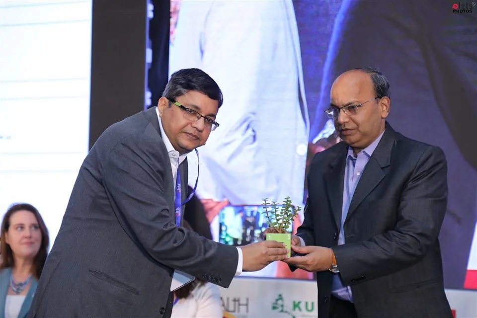 A sapling handed over between two delegates on stage